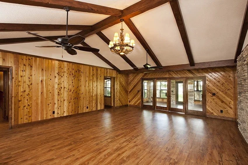 Great room with dark wood ceiling beams, pine-panelled walls and wood floors