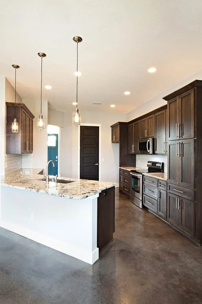 Kitchen with dark stained wood cabinets, a light quartz island and pendant lighting