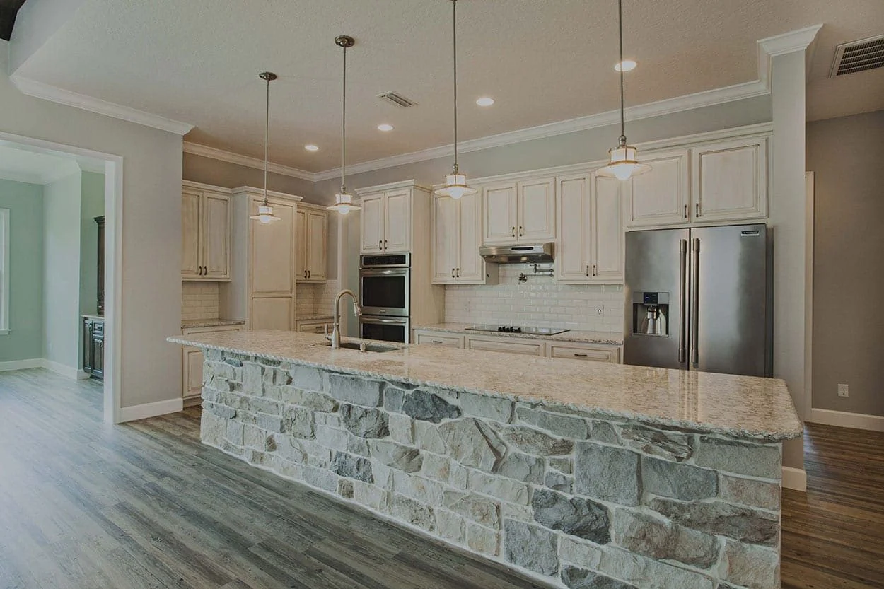 Kitchen with gray cabinets, a large island and three pendant lights