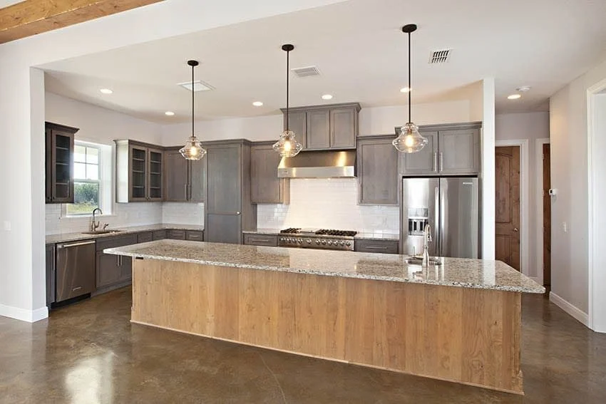Kitchen with gray shaker cabinets, a large granite island and stainless appliances