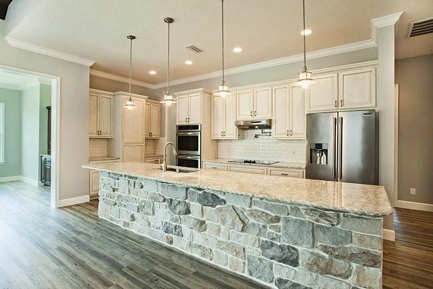 Kitchen with a stone-clad island, white cabinets and wood-look tile floor