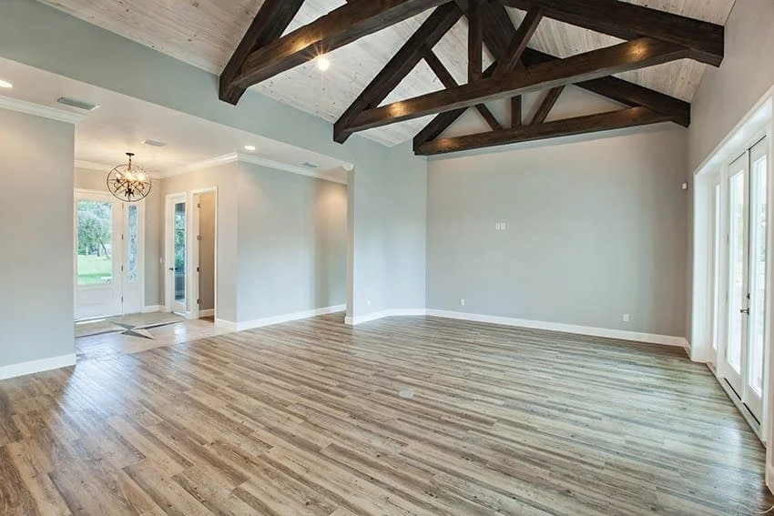 Open-plan living area with exposed wood ceiling beams and wood-look flooring