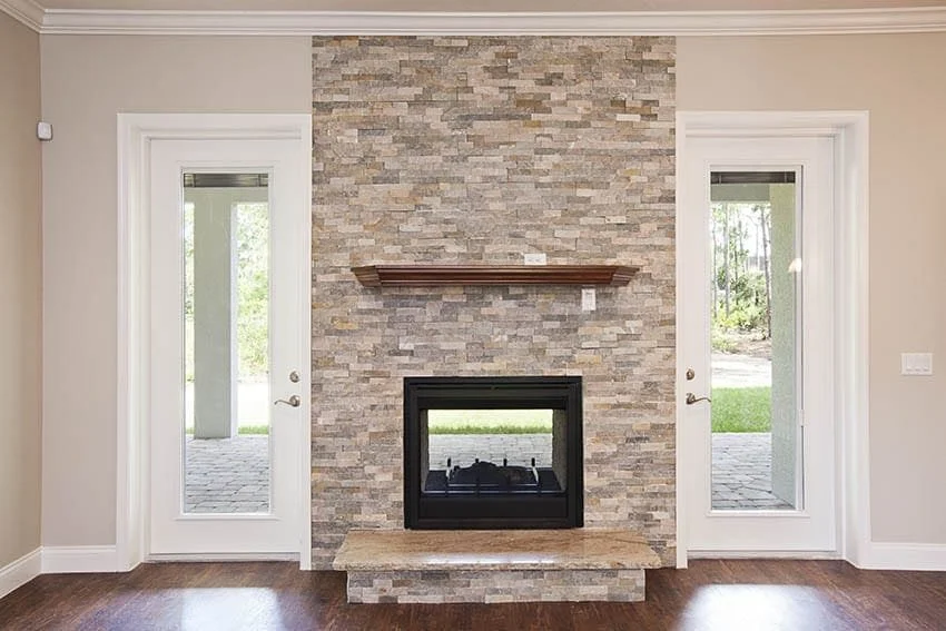 Living room with a floor-to-ceiling stacked-stone fireplace between two glass doors